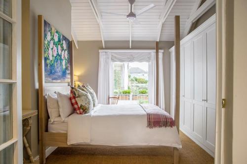 Un dormitorio con una gran cama blanca con ventana. en Charming Coastal Townhouse at The Majestic, en Ciudad del Cabo