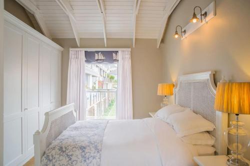 Un dormitorio con una cama blanca y una ventana. en Charming Coastal Townhouse at The Majestic, en Ciudad del Cabo