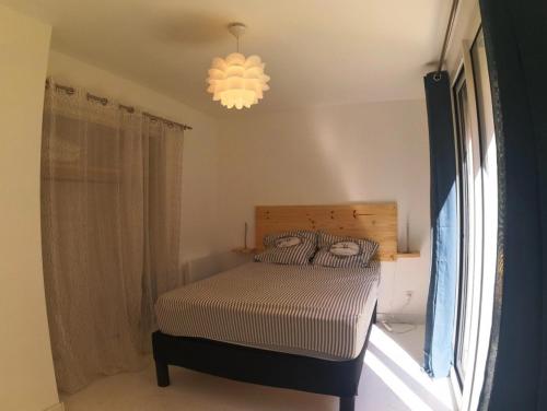 une chambre avec un lit et un lustre dans l'établissement T2 rénové à 50m de la mer, à Canet