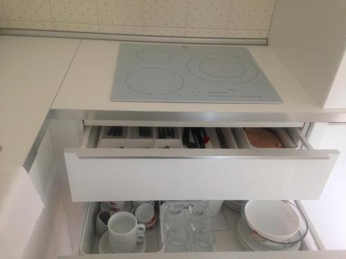 an open drawer in a kitchen with cups and dishes at Residence Geranio in Domaso