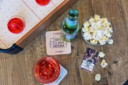 a table with a bottle of alcohol and a bowl of popcorn at Moxy Frankfurt Airport Kelsterbach in Kelsterbach
