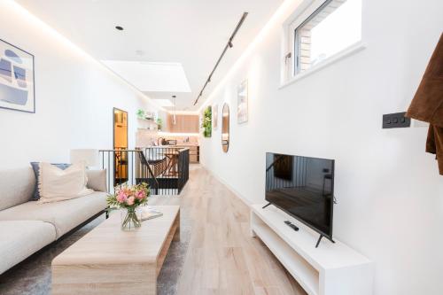 sala de estar con paredes blancas y TV de pantalla plana en Modern 1 bed House in Kensington High St, en Londres