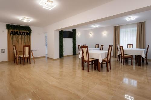 a dining room with white tables and wooden chairs at Vila AMAZON in Dubova