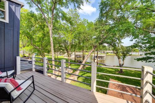 a wooden deck with chairs and a fence next to a river at Waterfront Gem on Cedar Creek Lake with Deck and Games in Enchanted Oaks