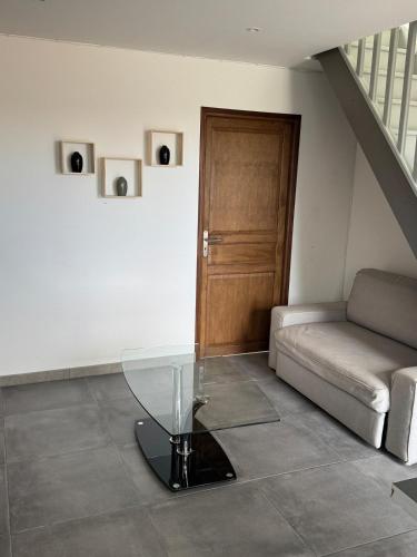 a living room with a glass table and a couch at Le repaire 2 in Saint-Omer-Capelle