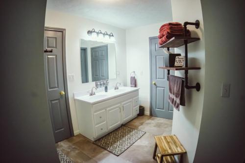 ein Badezimmer mit Waschbecken und Spiegel in der Unterkunft Resting Point - Hot Tub, Firepit, Spacious 4-BR Home in Rogers