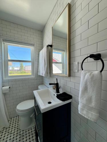 a bathroom with a sink and a toilet and a mirror at Cozy Whole Home Mid-Century Hideaway in Cody