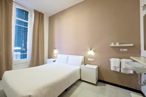 1 dormitorio con cama blanca y lavamanos en Pensión Peiró, en Barcelona