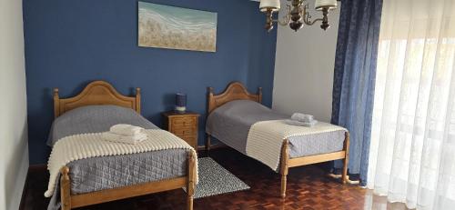 two twin beds in a bedroom with blue walls at Gomes & Fortunato House in Casais Brancos