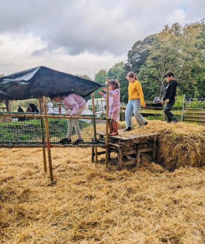 a group of people standing around a pile of hay at The stables farm stay private firepit bbq in Bramfield
