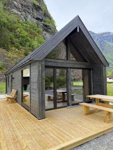 a black cabin with a wooden deck with a picnic table at Flåm Minisuite in Aurland