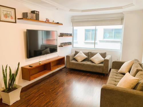a living room with two couches and a flat screen tv at San Diego Suites Confort, Vista & Estacionamiento en Cuenca in Cuenca