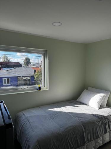 un dormitorio con una cama y una ventana en Departamento Studio Full 109, en Osorno