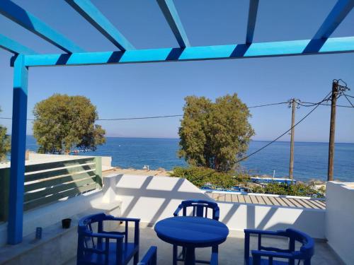 a view of the ocean from a patio with blue chairs at WHITE & BLUE Kamari in Kamari
