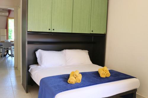 a bed with two pairs of yellow shoes on it at Villaggio Portorosa - La casetta tra le palme 14 in Torre Forte