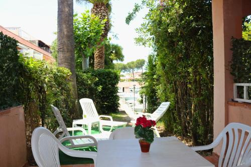 a table with white chairs and a vase with flowers at Villaggio Portorosa - La casetta tra le palme 14 in Torre Forte