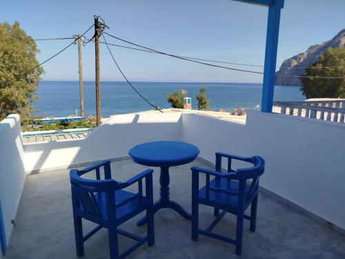 a blue table and two chairs on a balcony with the ocean at WHITE & BLUE Kamari in Kamari