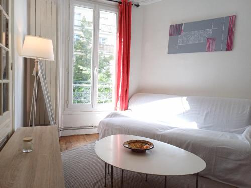 un salon avec un canapé blanc et une table dans l'établissement a calm double bedroom in F3 chez l'habitant Paris14eme parc Montsouris, à Paris