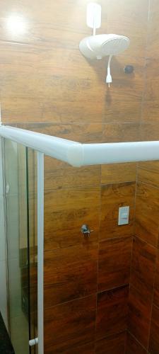 a bathroom with a glass shower with a wooden floor at Pousada Flor de Lins in Piranhas