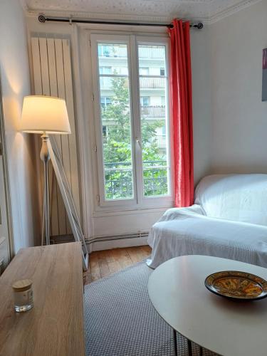une chambre avec un lit, une table et une fenêtre dans l'établissement a calm double bedroom in F3 chez l'habitant Paris14eme parc Montsouris, à Paris