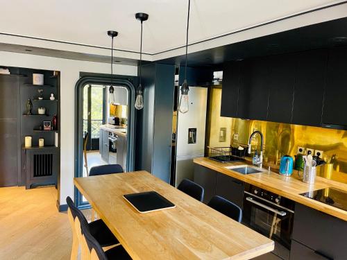 une cuisine avec une table en bois et des armoires noires dans l'établissement Le Marais by Steph, à Paris