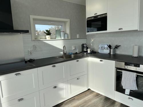 a kitchen with white cabinets and a sink and a window at Entire cottage with sea view in Stråvalla