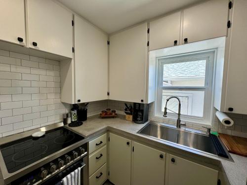 a kitchen with white cabinets and a sink and a window at Cozy Whole Home Mid-Century Hideaway in Cody