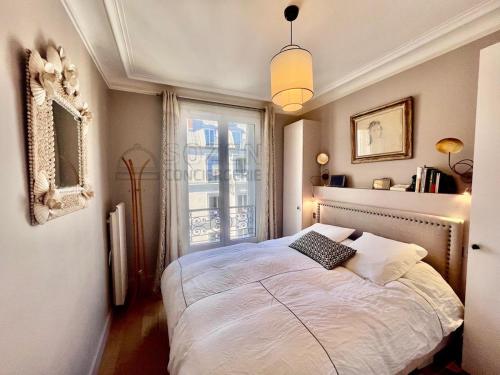 une chambre avec un grand lit avec une fenêtre dans l'établissement Au pied de la promenade Pereire - Paris 17, à Paris