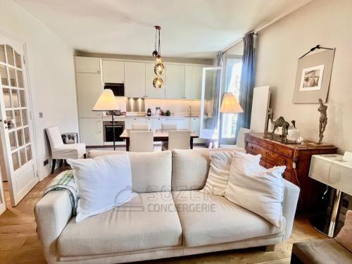 un salon avec un canapé blanc et une cuisine dans l'établissement Au pied de la promenade Pereire - Paris 17, à Paris
