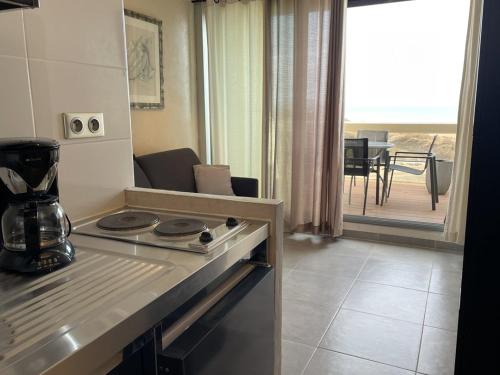 Il comprend une cuisine équipée d'une cuisinière. - un four supérieur à côté d'un salon dans l'établissement Studio Héliopolis AB 414 - 2 personnes, au Cap d'Agde