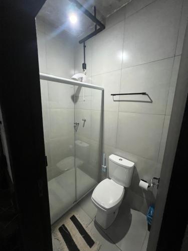 a bathroom with a toilet and a glass shower at Esquina 8 Suítes Confort & Hostel in Florianópolis