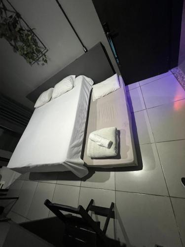 a bed with white sheets and pillows on the floor at Esquina 8 Suítes Confort & Hostel in Florianópolis