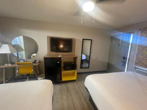 a hotel room with two beds and a television at Days Inn by Wyndham Holladay in Holladay