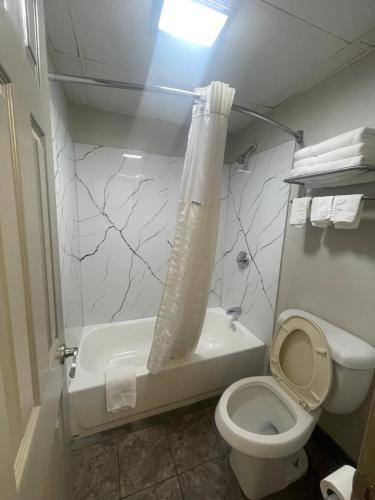 a bathroom with a toilet and a tub and a sink at Days Inn by Wyndham Holladay in Holladay