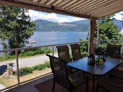 a table and chairs on a porch with a view of a lake at West facing Waterfront Retreat with private beach, dock access & private buoy in Blind Bay