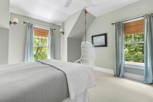 a white bedroom with a swinging bed and windows at The Ponchartrain in New Buffalo