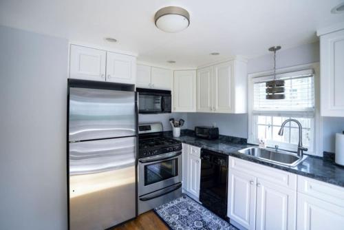 a kitchen with white cabinets and a stainless steel refrigerator at Coastal Haven in Dennis