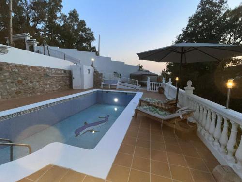 a swimming pool with an umbrella next to a house at Villa relax todo verde natural in Almuñécar