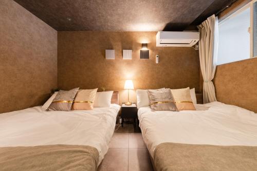 two twin beds in a room with a lamp at Luxury Tokyo Stay I 120sqm 4LDK I Close to Shibuya & Shinjuku Area in Tokyo
