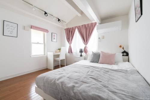 a white bedroom with a large bed with pink pillows at Luxury Tokyo Stay I 120sqm 4LDK I Close to Shibuya & Shinjuku Area in Tokyo