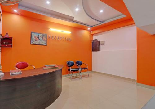 a reception room with orange walls and two chairs at Hotel O Sri Krishna Palace in Lucknow