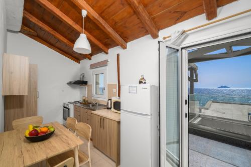a kitchen with a table and a white refrigerator at Pelagos Home, Liatiko Suite in Kalamaki Heraklion
