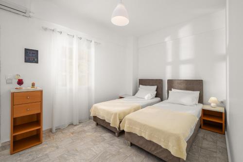two beds in a bedroom with white walls and a dresser at Pelagos Home, Liatiko Suite in Kalamaki Heraklion