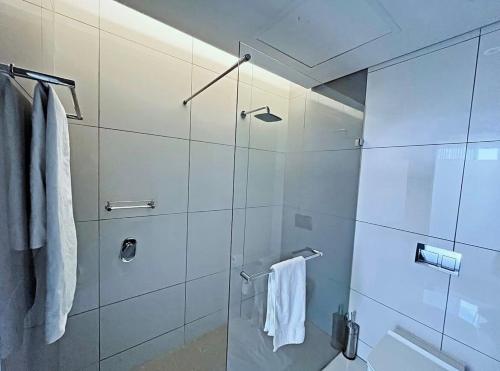 a bathroom with a glass shower with white towels at Stunning City View Apartment Sandton City-The Capital On The Park in Johannesburg
