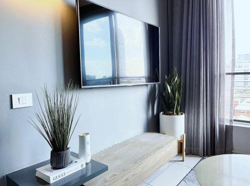 a living room with two potted plants and a mirror at Stunning City View Apartment Sandton City-The Capital On The Park in Johannesburg
