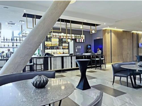 a restaurant with tables and chairs and a bar at Stunning City View Apartment Sandton City-The Capital On The Park in Johannesburg