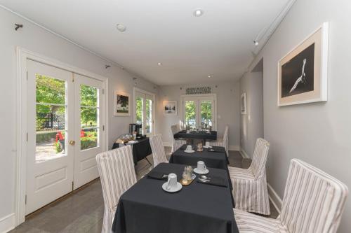 a dining room with two tables and white chairs at The Old Bank House in Niagara on the Lake