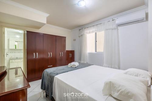 a bedroom with a large white bed and a window at Aptos completos a passos do mar em Meia Praia – OBS in Perequê