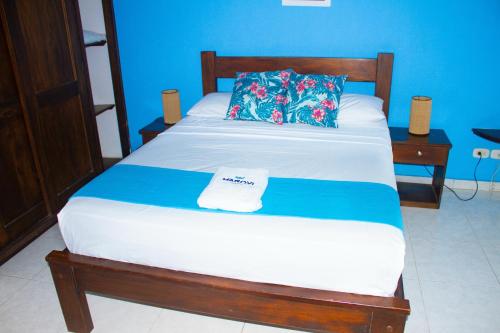 a bed in a room with a blue wall at Hotel Marovi in Santa Marta