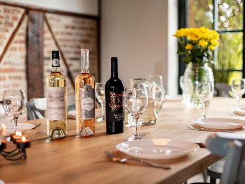 a wooden table with two bottles of wine and glasses at Alverwege 2 in Baerle Heide